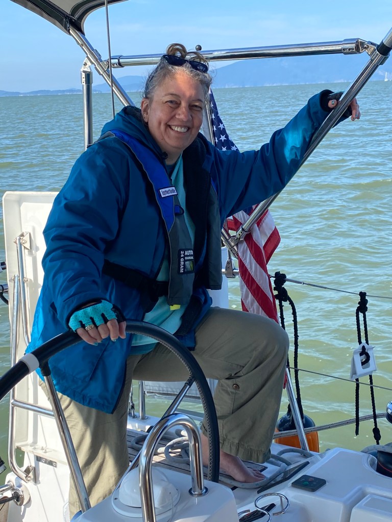author at the helm of a sailboat, barefoot