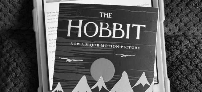 social media icons on a tablet, next to a paperback book