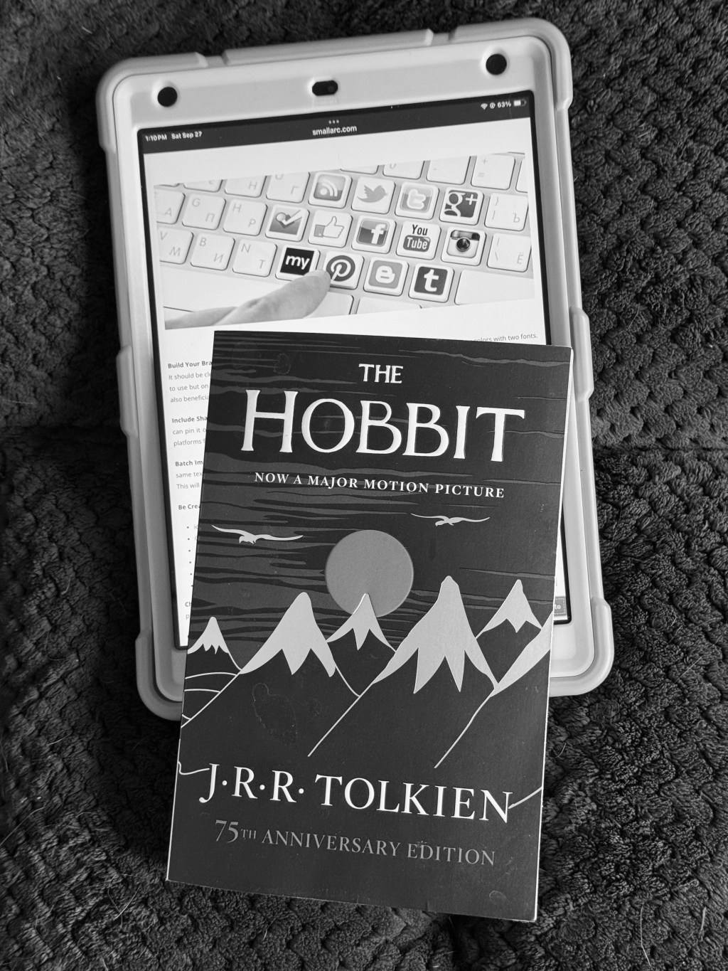 social media icons on a tablet, next to a paperback book