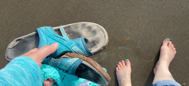 bare feet (with dangling sandals) on a beach