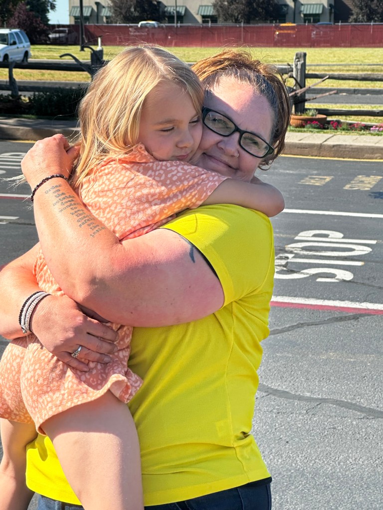 photo of a staff member hugging another staff member's daughter