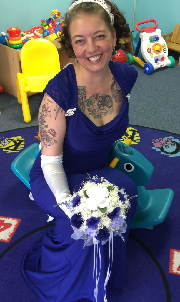photo of the writer in a blue wedding dress, sitting on a rocking horse in a children's nursery