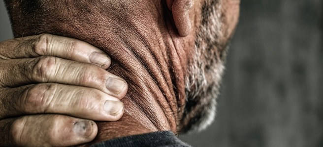 a man grips the back of his neck, indicating pain