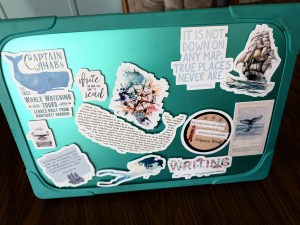 laptop computer in a turquoise case with stickers about whales, books, and writing